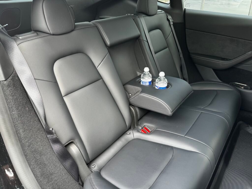 Intérieur d’une Tesla Model Y noire avec siège en cuir et bouteille d’eau – Chauffeur privé à Nice Côte d’Azur

